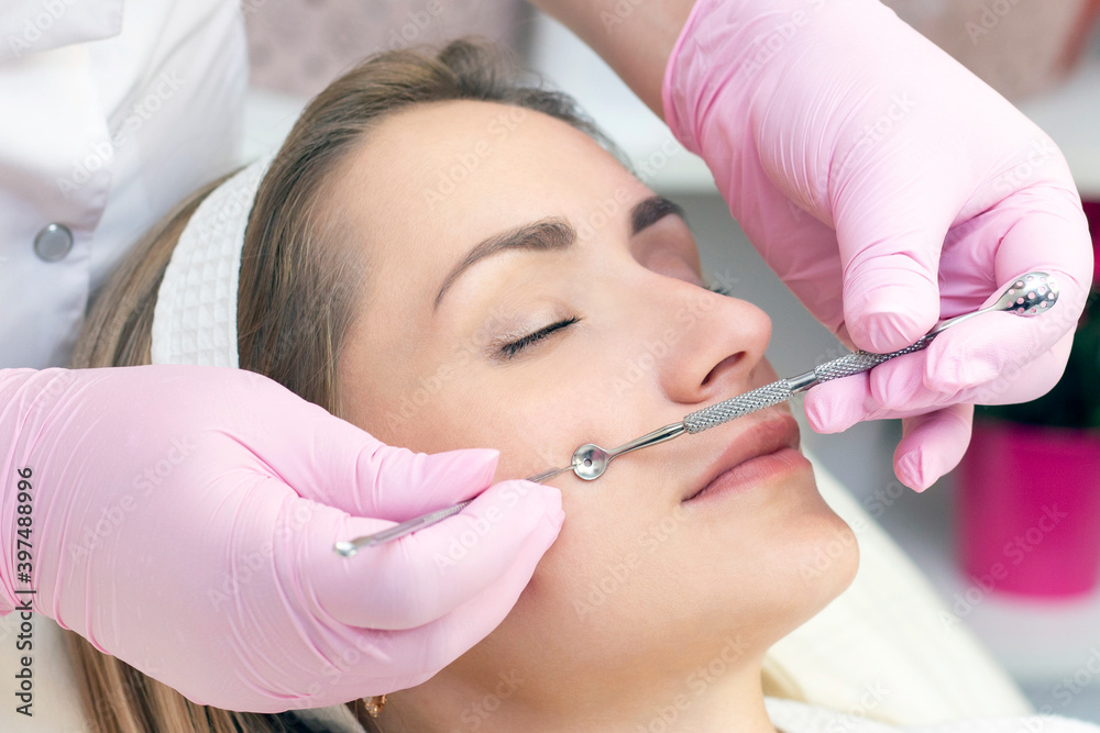 Procedure for cleaning the skin of the face with a steel appliance with a spoon from blackheads and acne.