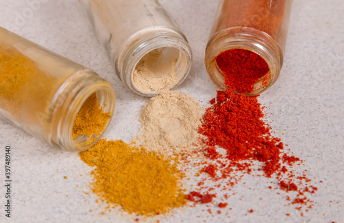 Jars with different scattered assortment of spices, white pepper, chili flakes, lemongrass, coriander and cumin seeds in jars on kitchen. Top view. Advertising