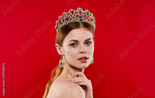 portrait of a confident woman on a red background with a crown on her head