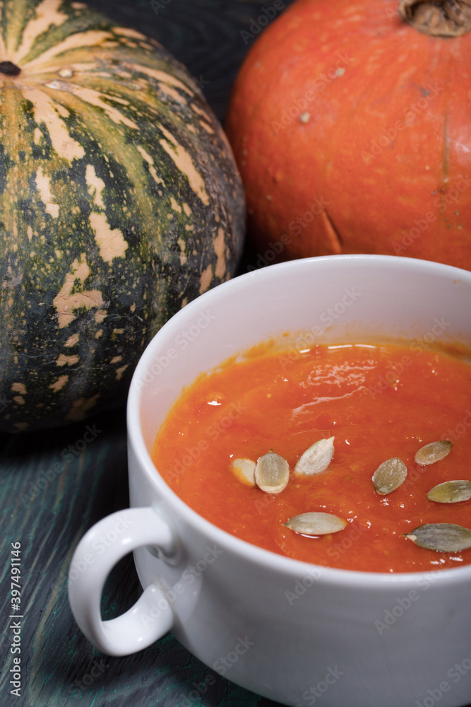 Pumpkin tomato cream soup. With the addition of pumpkin seeds. Several pumpkins are nearby. On pine boards. Pumpkin tomato cream soup. With the addition of pumpkin seeds. Several pumpkins are nearby. On pine boards.