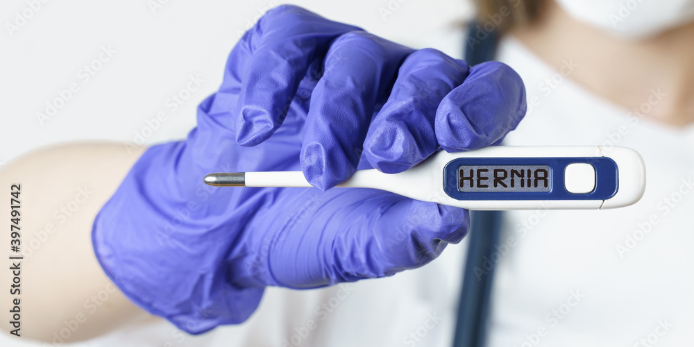 The doctor holds a thermometer in his hands, on the electronic screen of which it is written - HERNIA