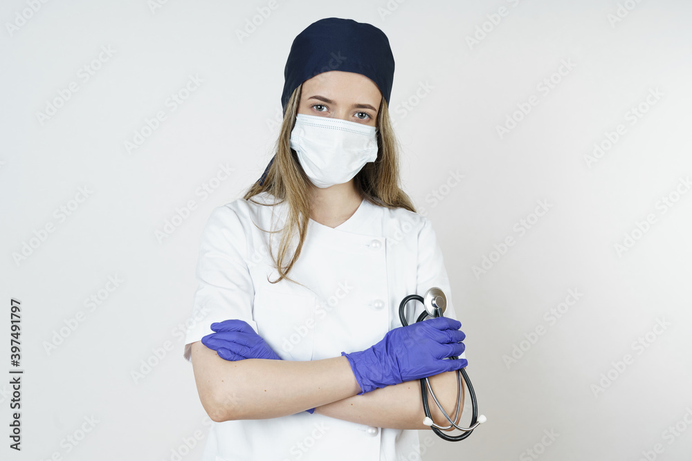 Medicine and health concept. Portrait of a doctor in a mask and headdress with a stenoscope in his hands. Medicine and health concept. Portrait of a doctor in a mask and headdress with a stenoscope in his hands.