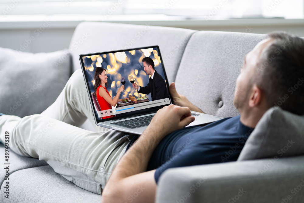 Young Man Lying On Sofa Watching Video