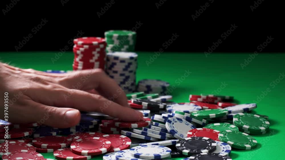 Hand counts poker chips lying on a green table on black background in close-up. Concept of playing hazard games in casino. Theme of winning and losing money. Gambling as entertainment at leisure time. Hand counts poker chips lying on a green table on black background in close-up. Concept of playing hazard games in casino. Theme of winning and losing money. Gambling as entertainment at leisure time.