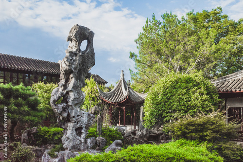 Giant rock in garden by Chinese architecture at Lingering Garden Scenic Area, Suzhou, Jiangsu, China