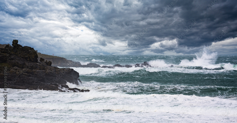 Dramatic stormy sea and thunderous sky with large waves crashing onto rocks