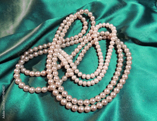 necklaces made of white pearls on a background of green shiny silk