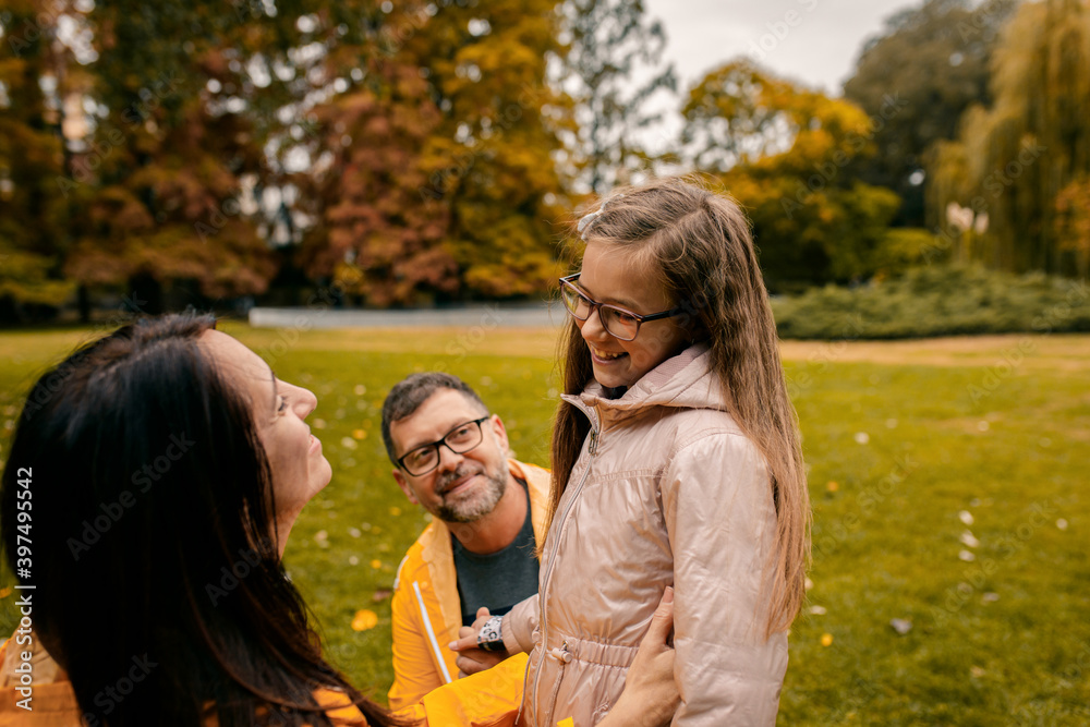 Fototapeta premium Family of three in raincoat enjoying together in city park after rain.
