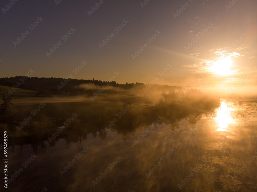 Misty lake with fog rises above the water at dawn. Autumn scenery.