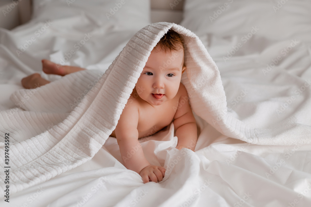 Cute toddler boy lies on bed with plaid on his head Cute toddler boy lies on bed with plaid on his head