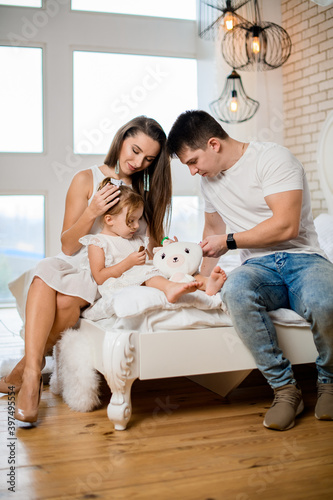 view of happy family couple with child sitting on bed