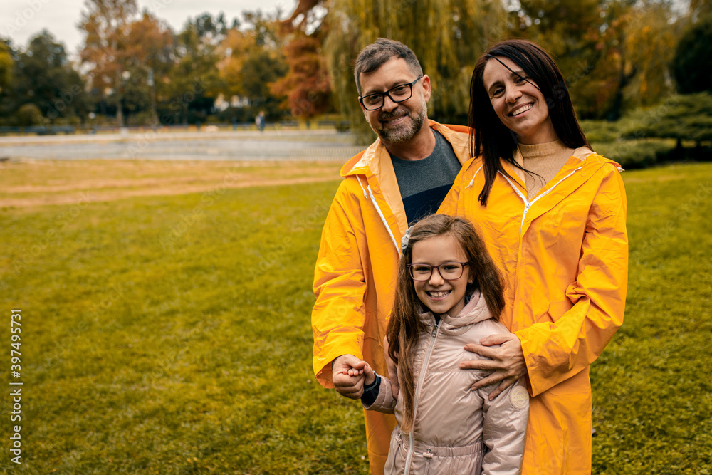 Family of three in raincoat enjoying together in city park after rain. Family of three in raincoat enjoying together in city park after rain.