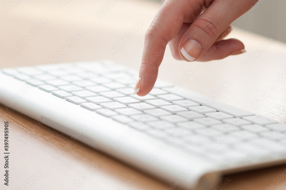 Female finger pressing key on a keyboard Female finger pressing key on a keyboard