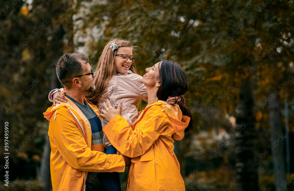 Family of three in raincoat enjoying together in city park after rain. Family of three in raincoat enjoying together in city park after rain.