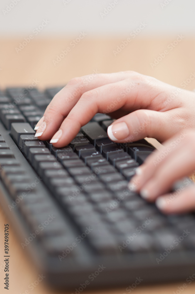 Close-up of hands typing on a keyboard in an office Close-up of hands typing on a keyboard in an office