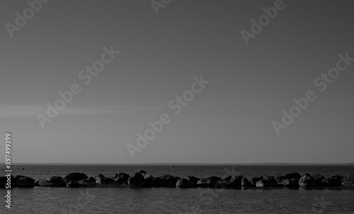 Black and white seascape with line of stones against the waves