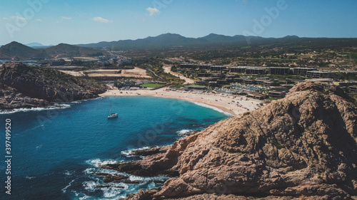 Small beach surrounded by mountains with clear blue water with a sailing boat in Mexico