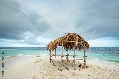 Wooden gazebo with palm tree leaves roof on the white sand of the paradise beach in Atlantic Ocean, Cayo Arena, Punta Rucia, Dominican Republic