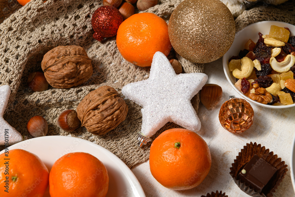 Fototapeta premium sweet food background for christmas or holiday decoration - chocolate candies, tangerines, nuts and dried fruits on white wood