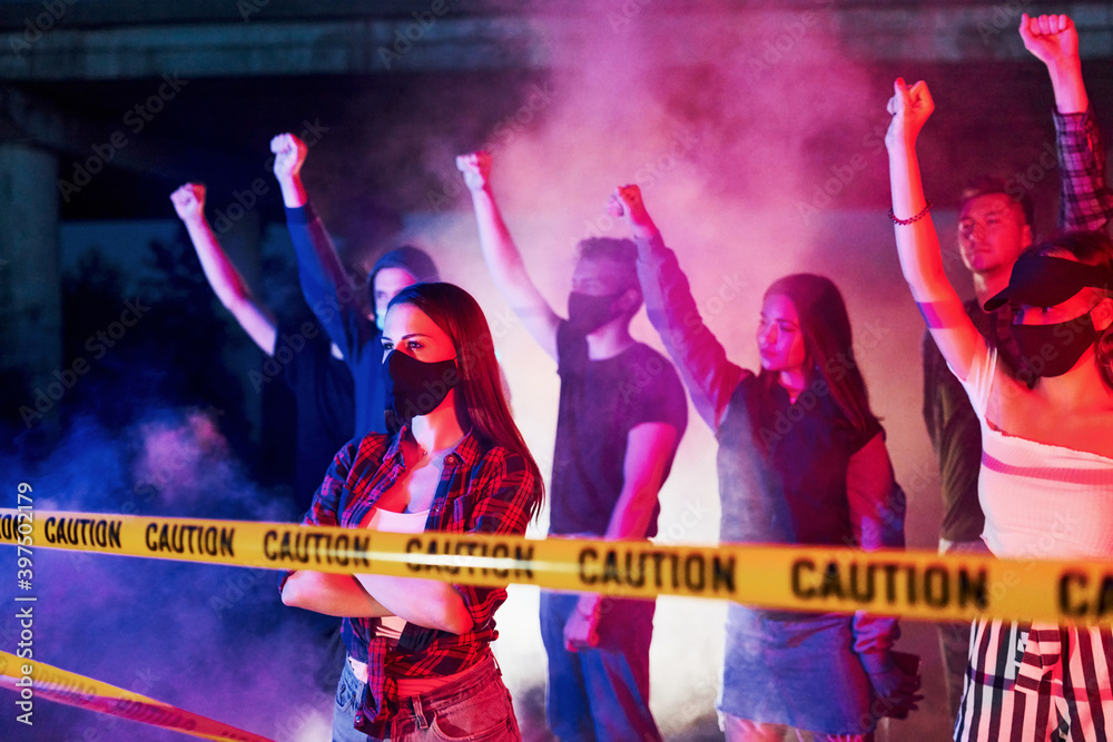 Fototapeta premium Police line and smoke. Group of protesting young people that standing together. Activist for human rights or against government