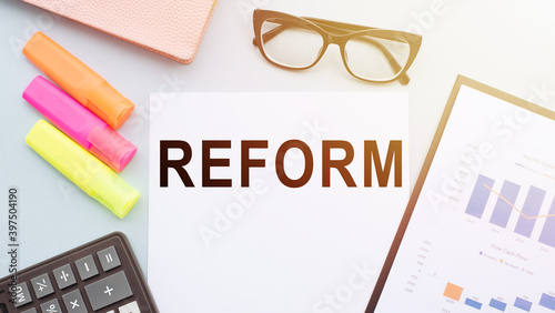 REFORM a word on your desktop with a calculator, markers, glasses and financial charts.