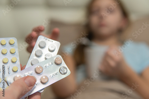 Girl with dark hair gets sick in bed and takes pills. close-up