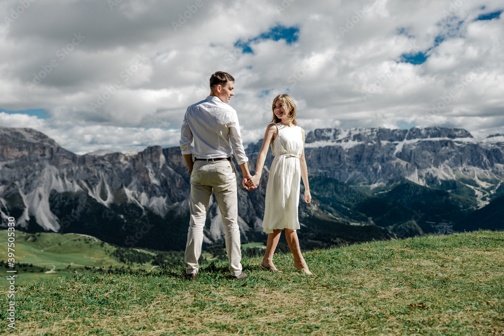couple in love hold hands on the top of the mountain from where a fantastic view of the mountains opens up. the groom and the bride in the dolomites. wedding day in the mountains. honey month. 
