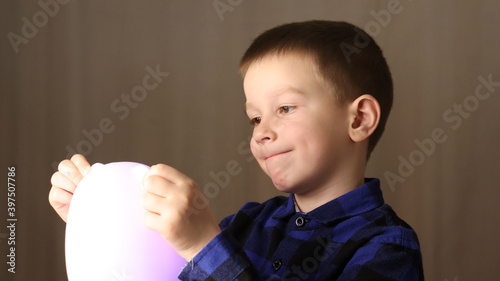 a child in a blue shirt holds a lamp in the form of a hare in front of him