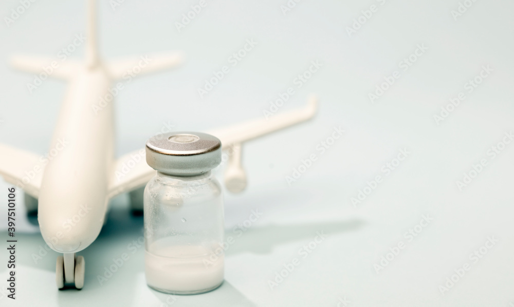 vaccine in glass vial, with white plane, blue background vaccine in glass vial, with white plane, blue background
