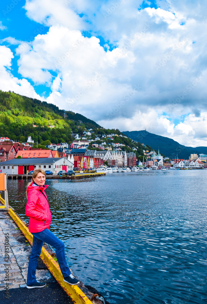 Φωτογραφία Girl tourist on the background of the sea bay and old wooden houses on the embankment of Bergen