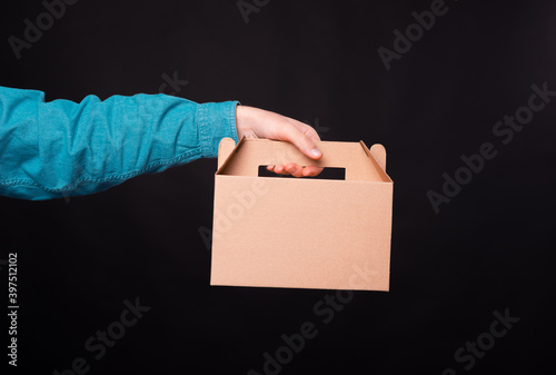 Male hand holding delivery food box over dark background. photo