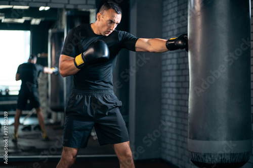 athletic sport man boxer training with punching bag or exercising in gym © goami