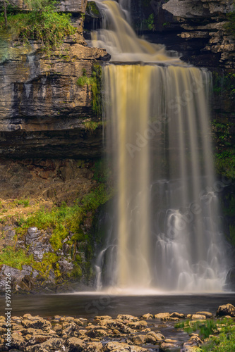 Waterfalls cascade surrounded by greenery and rocks