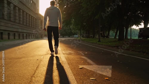 rear male with dog walk at dawn empty morning city walks at sun rays slow motion