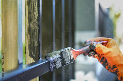 Worker painting steel with paint brush and orange gloves selective focus on hand photo