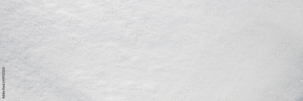 Beautiful winter background with snowy ground. Natural snow texture. Wind sculpted patterns on snow surface. Wide panoramic texture for background and design. Closeup top view with copy space.