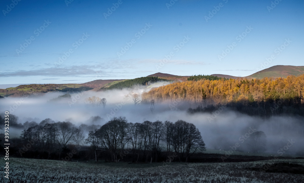 the mist at the bottom of the welsh valley with the top of the mountains peaking out of the clouds