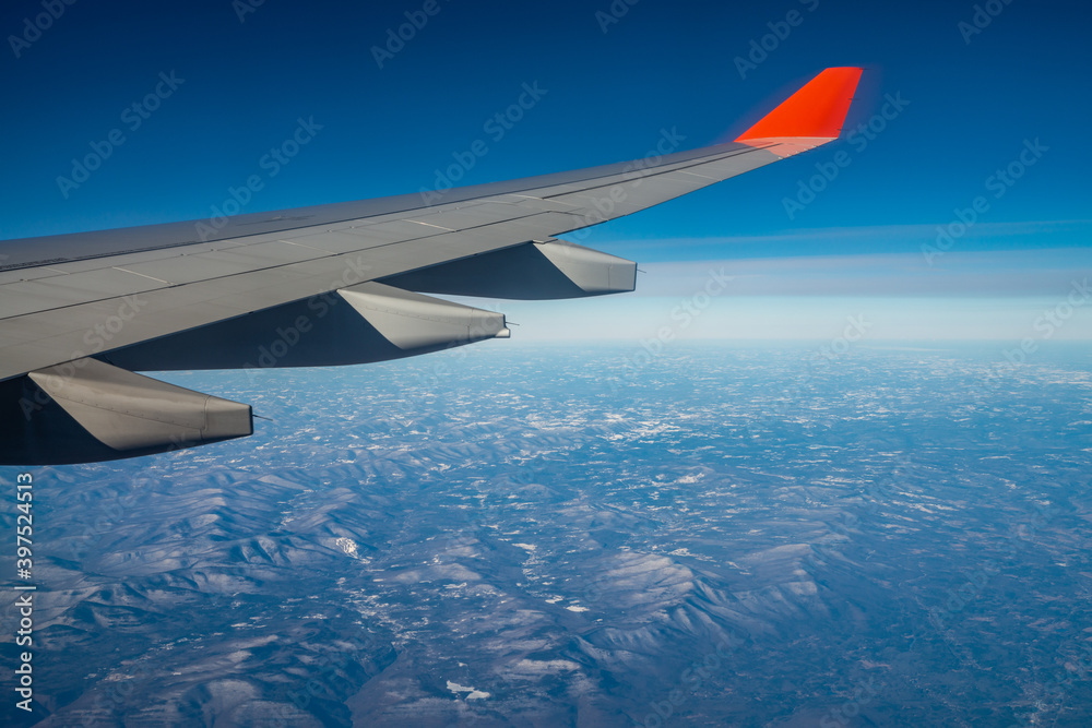 Obraz premium Plane wing with blue clear sky and mountains