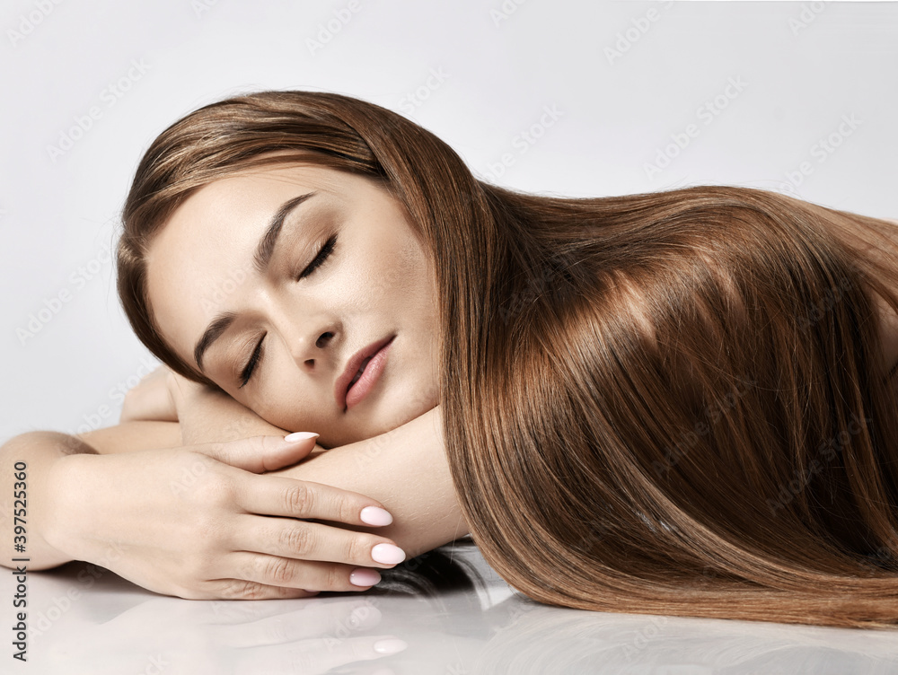 Portrait of young pretty woman model with silky long straight hair lying and relaxing with eyes closed over white background. Hairstyle, hairsalon, hairdresser, fashion concept Portrait of young pretty woman model with silky long straight hair lying and relaxing with eyes closed over white background. Hairstyle, hairsalon, hairdresser, fashion concept