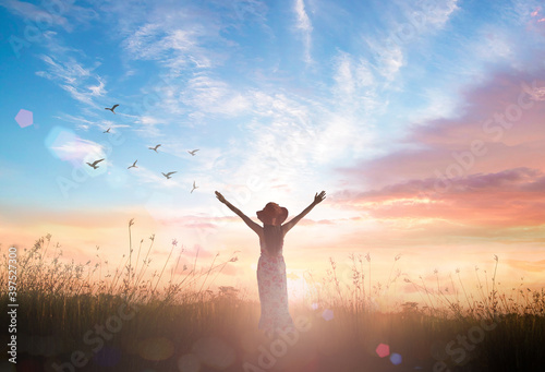 Silhouette of healthy woman raised hands for praise and worship God at autumn sunset meadow background