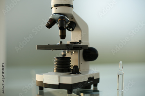 Ampoule with a vaccine and a microscope on a glass table