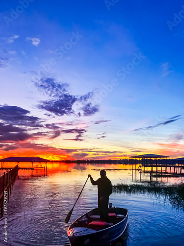 Silhouette of a man with a paddle on a boat on the lake against the background of a colorful sunset on Lake Letta in Florida