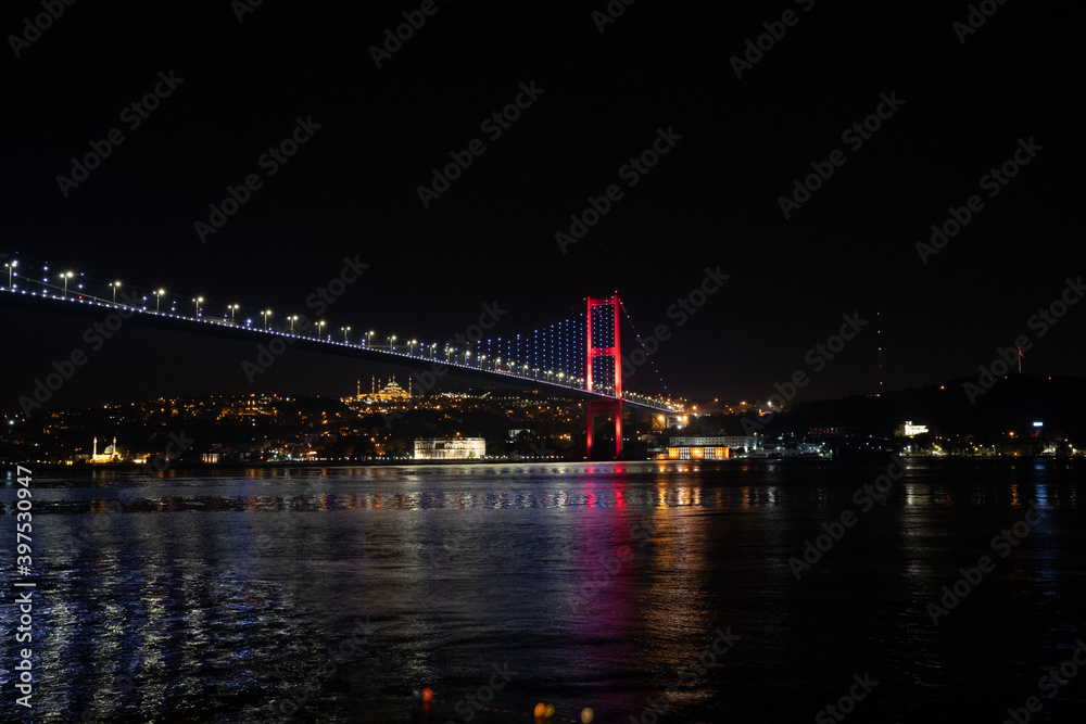 Bosporus Bridge at night with the city lights reflecting to the sea.Istanbul bridge at night