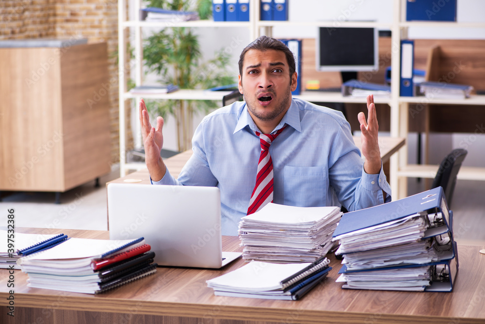Young male employee unhappy with excessive work Young male employee unhappy with excessive work