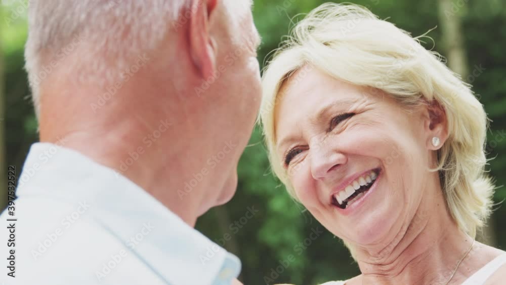 Close up of loving senior couple hugging and kissing in garden at home together - shot in slow motion Close up of loving senior couple hugging and kissing in garden at home together - shot in slow motion