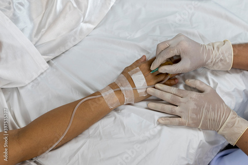 Nurse hand preparing a saline tube for infuse patient arm in the hospital.