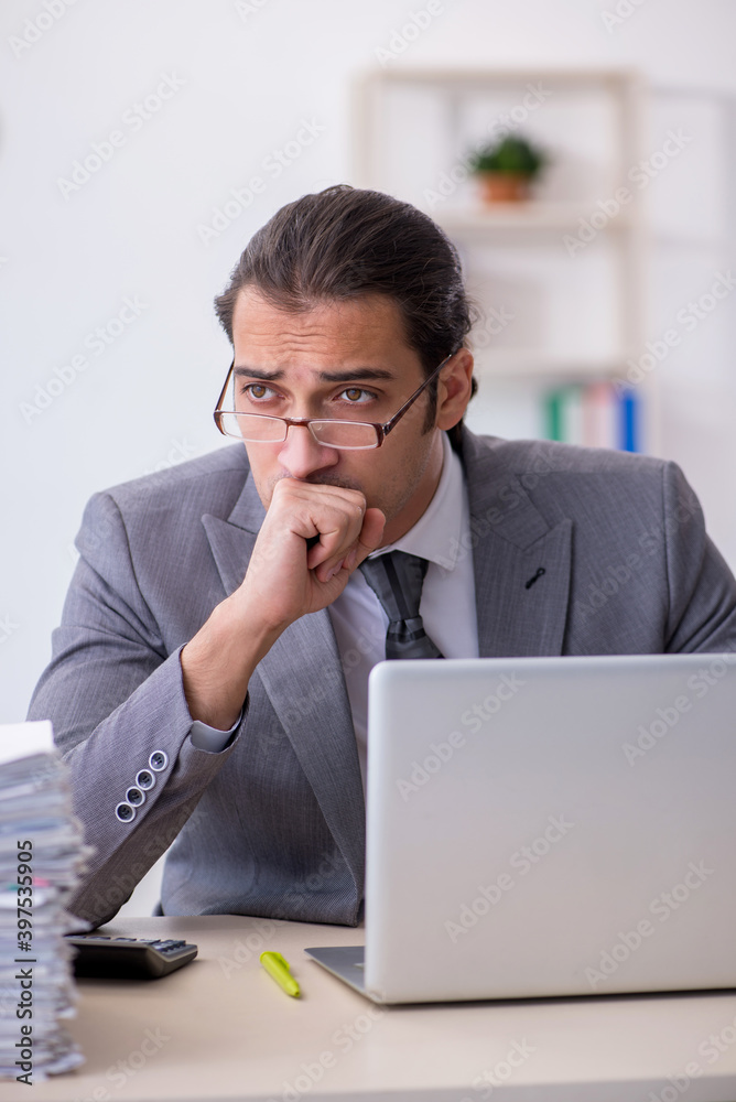 Young male employee unhappy with excessive work in the office Young male employee unhappy with excessive work in the office