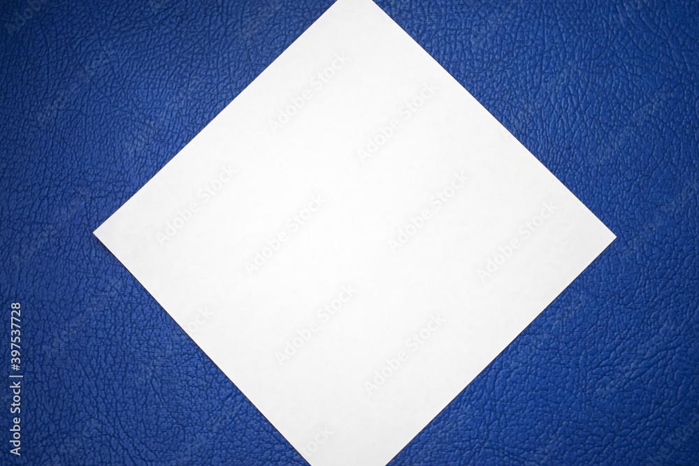 a rhombus in the form of a white leaf lies on a blue textured background. Concept photo a rhombus in the form of a white leaf lies on a blue textured background. Concept photo