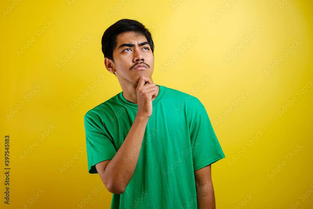 Asian man in green t-shirt thinking something, looking for good idea