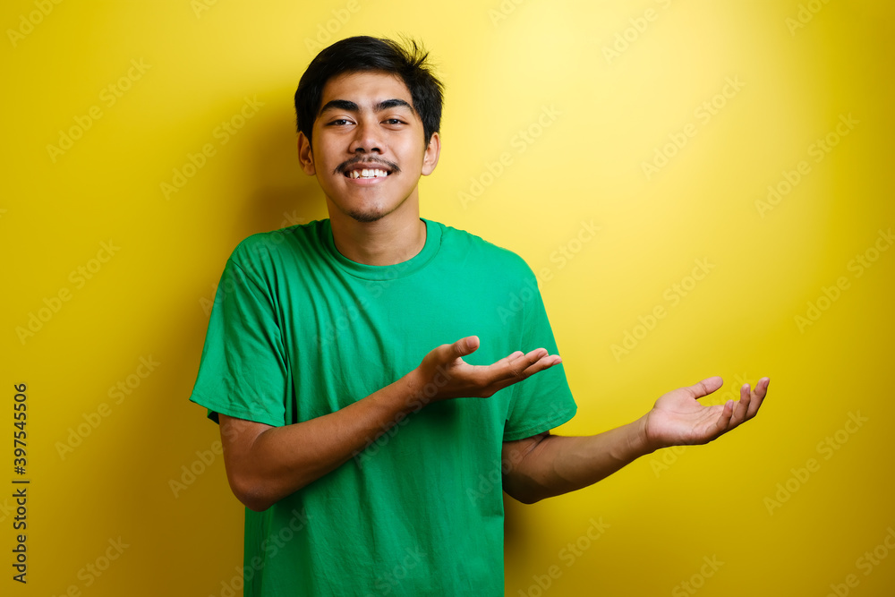 Smiling handsome Asian man pointing finger to empty open hand Smiling handsome Asian man pointing finger to empty open hand